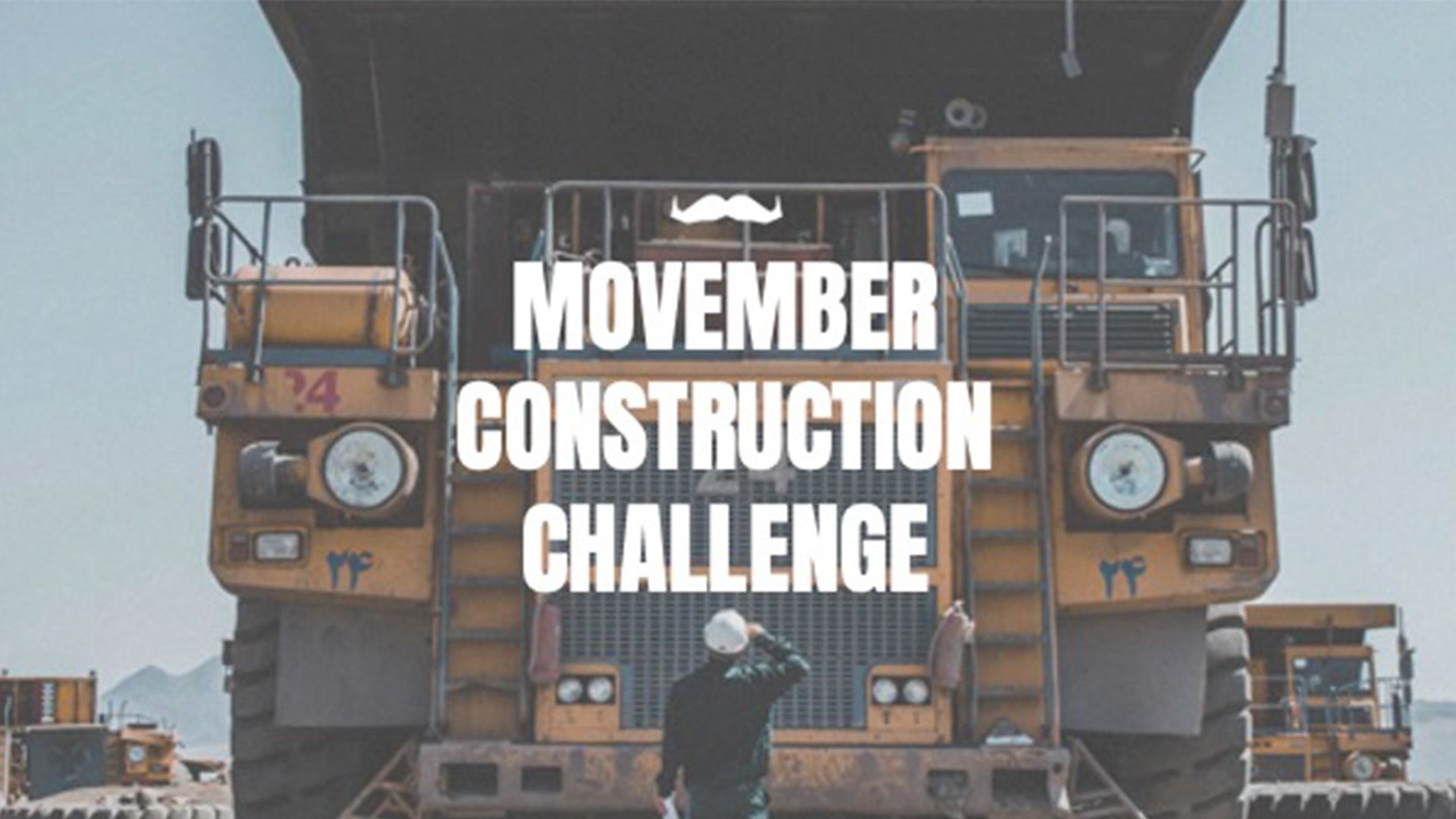 Photo of a man in a construction hat looking up at a large piece of construction machinery.