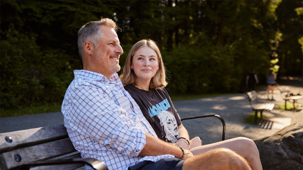 Photo of a father sitting on a bench with his daughter.